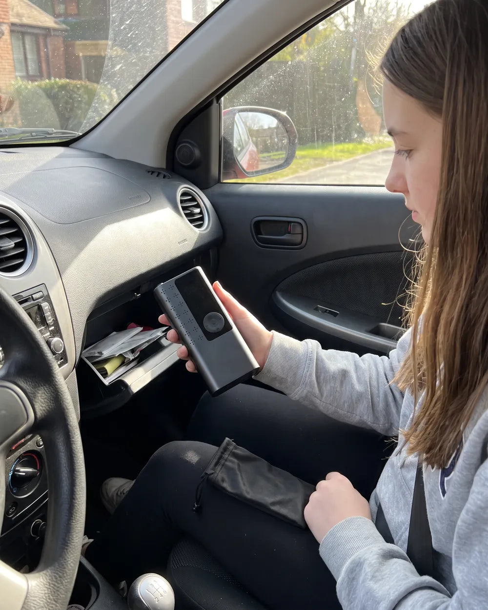 Une jeune conductrice range AirRove dans la boîte à gants