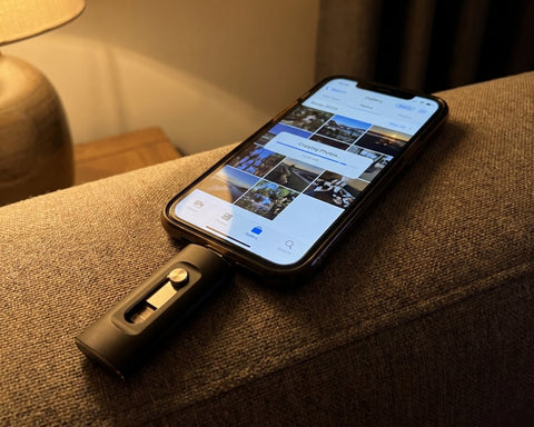 Fotostick in Schwarz steckt am Handy auf dem Sofa